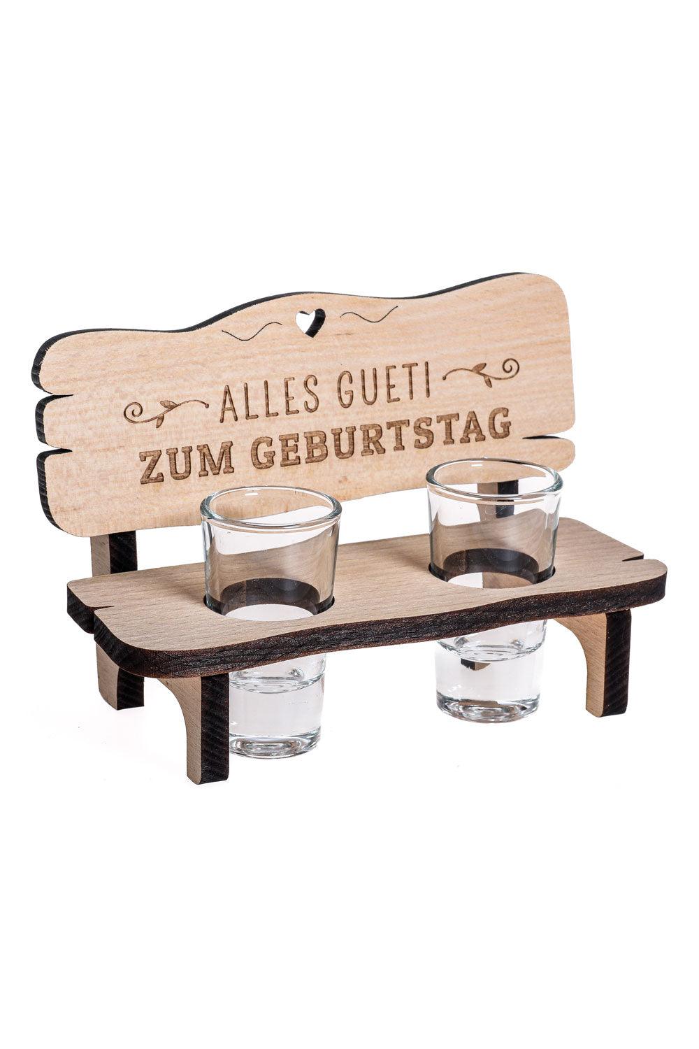 Das Schnapsgeschenk ist ein optimales Geschenk fuer alle, die gerne Schnaps trinken. Auf der Schnapsbank steht auf Mundart die Aufschrift: Alles Gueti zum Geburtstag. Das kleine Holzbaenkli kann mit einer Flasche Schnaps verschenkt werden. Inklusive 2 Schnapsglaesli aus Glas. Ein perfektes Geschenk zum Geburtstag.