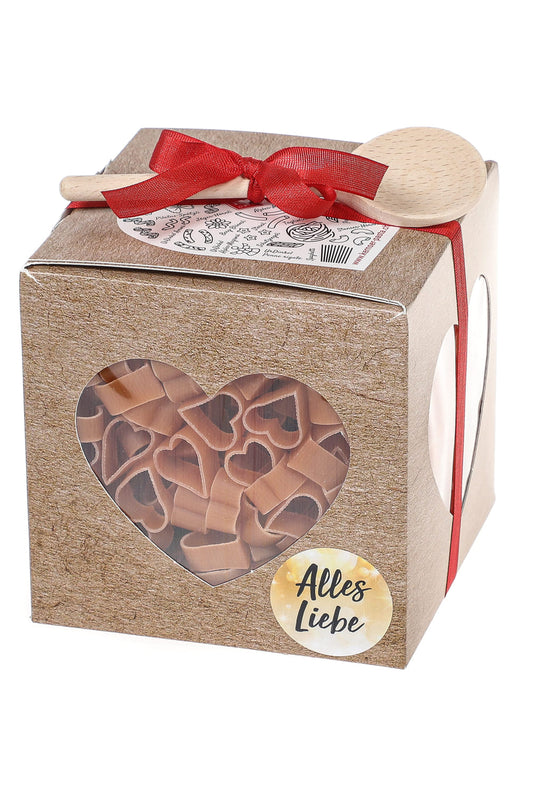 Herzpasta ist in einer schoenen Geschenkbox mit roter Schlaufe und einem Holz Kochloeffel. Der Herz Pastawuerfel mit Spruchetikette: Alles Liebe.