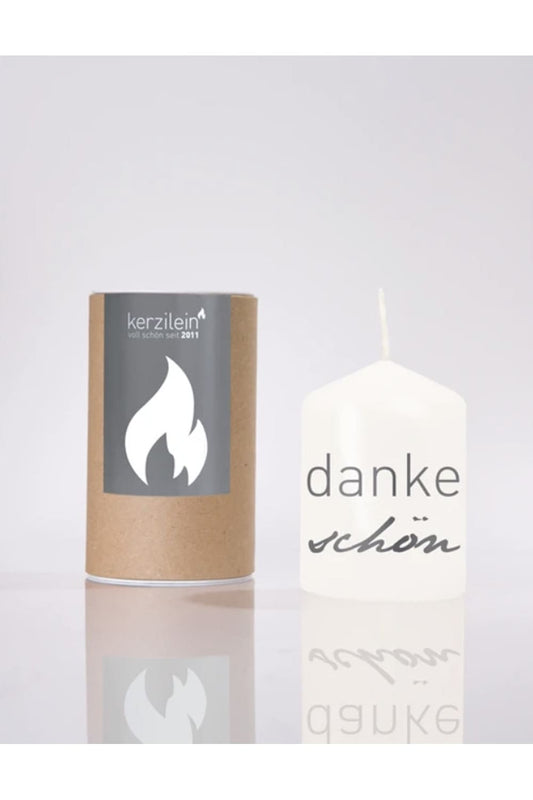 Flaemmchen von Kerzilein! Auf der Kerze befindet sich der Spruch: Dankeschoen! Die Stumpenkerze ist weiss und verpackt in einer runden Kartonverpackung. 