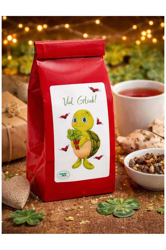 Spruch-Tee mit der Aufschrift: Viel Glueck, und der niedlichen Schildkroete Lia. Die Schildkroete haelt einen Strauss voller vierblaettrigen Kleeblaettern in der Hand. Glueckstee fuer jeden Anlass! 